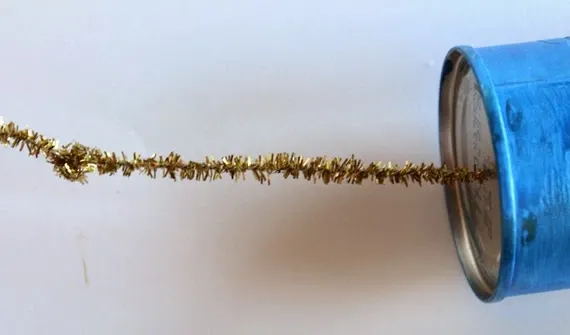 DIY recycled tin can craft - gold pipe cleaner poked through center of tin can to assemble windchime DIY recycled tin can craft - gold pipe cleaner poked through center of tin can to assemble windchime